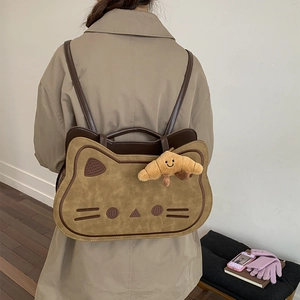 Detail of cute cat shaped backpack with plush croissant charm and rich faux suede texture