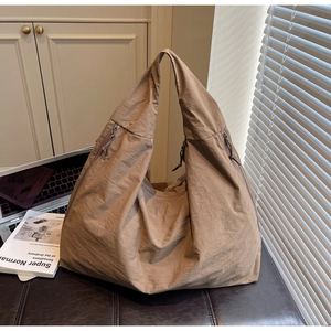 Détail du grand sac hobo en nylon marron café avec fermetures éclair latérales dans un bureau