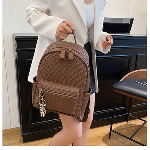 Detail view of dark brown woven PU leather backpack with a cute silver bear charm