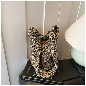 Detailed view of the leopard print faux fur bucket bag resting on a decorative book