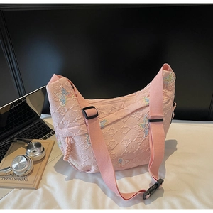Detail of pink quilted crossbody bag with butterfly embroidery and wide adjustable strap