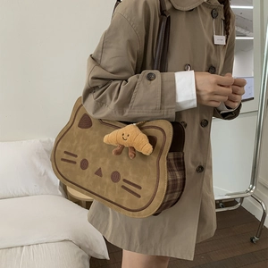 Cute caramel cat backpack with croissant plush charm shown on a khaki trench coat
