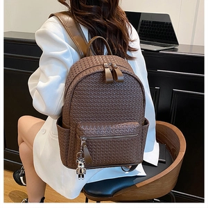 Detail of dark brown woven leather backpack with silver bear charm and padded straps