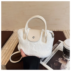 Close-up of white plush bucket bag with beige PU handle and metal buckle on table