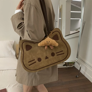 Close-up of cute cat-shaped crossbody bag with soft texture and a croissant plush charm