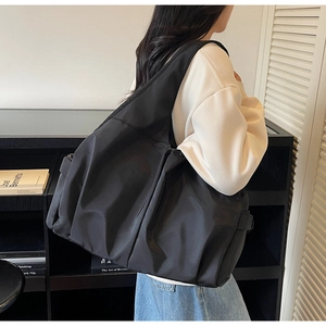 Détail d'un grand sac cabas en nylon noir avec texture plissée et large bandoulière