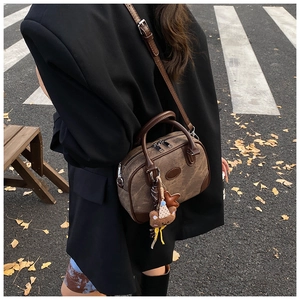 Detail of vintage brown canvas and leather boston bag with a cute bear plush charm