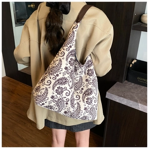 Detail of bohemian paisley print tote bag with brown leather strap in use by a model