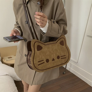 Close-up of cat-shaped crossbody bag featuring plaid side details and adjustable leather strap