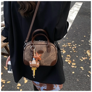 Close-up of vintage canvas Boston bag with plush bear charm and leather strap detailing