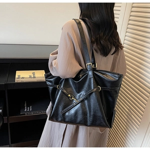 Close-up of black leather tote bag featuring natural texture and gold metal accents