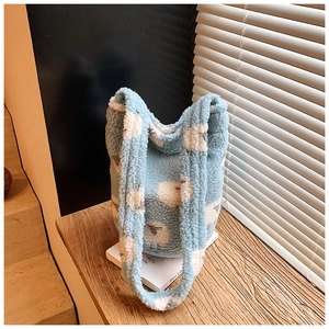 Close-up of light blue fleece bucket bag with white sheep patterns on a wooden surface