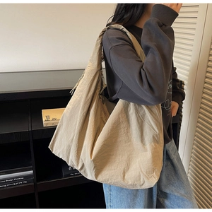 Détail du sac fourre-tout beige avec large bandoulière et texture en tissu plissé