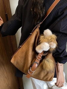 Caramel woven bucket bag with brown leather strap and decorative charm on model