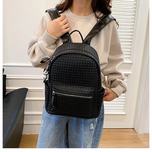 Close-up of black woven leather backpack showing intricate texture and side pocket