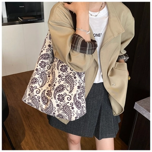 On-shoulder view of a large purple paisley canvas tote bag styled with a khaki blazer