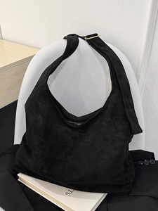 Grand sac cabas minimaliste en daim noir avec bandoulière réglable sur chaise blanche