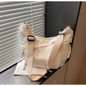 Detailed quilted half-moon bag featuring colorful butterfly embroidery and adjustable strap
