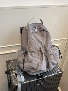 Gray nylon outdoor backpack with drawstring pockets on silver metallic luggage