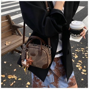 Close-up of vintage brown Boston bag with star and bear charms in an autumn street setting