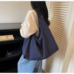 Vue détaillée d'un grand sac fourre-tout bleu marine au design souple et décontracté