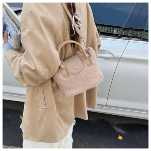 Model wearing a fuzzy plush crossbody bucket bag in light apricot with PU leather trim