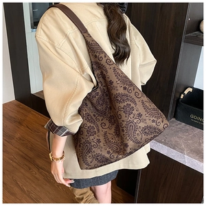 Detail view of large paisley print tote bag with brown leather shoulder straps