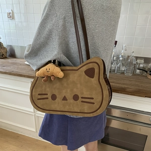 Detail of cartoon cat crossbody bag with embroidered face and plush croissant charm