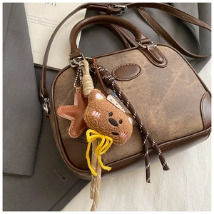 Detailed view of dark brown vintage pillow bag with bear and star charms decoration