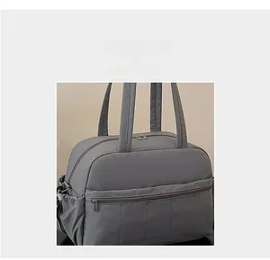 Detail of dark grey travel bag showing multiple front pockets and durable nylon texture
