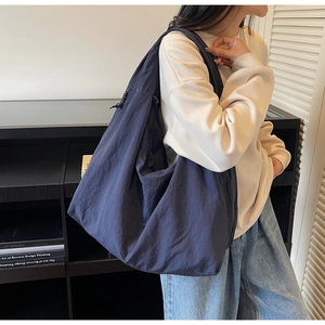 Détail du grand sac à bandoulière bleu marine avec cordon latéral et texture en nylon