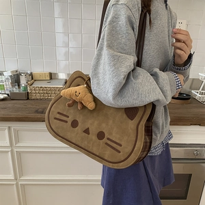 Close-up of cat-shaped brown shoulder bag with croissant charm and plaid fabric detail