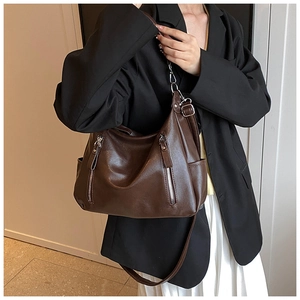 Detail of dark brown vintage faux leather tote bag with silver zippers and side pockets