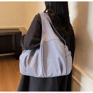Vue arrière d'un grand sac cabas en nylon lilas avec design plissé porté à l'épaule