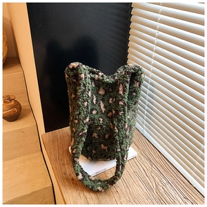 Close-up of green leopard print plush bucket bag with fuzzy wool texture on wood surface
