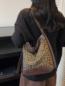 Large leopard print bucket bag with brown leather straps shown on a model