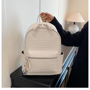 Detail of off-white woven leather backpack with bow zippers and silver bear charm