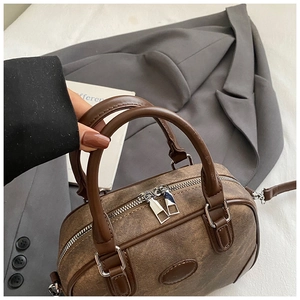 Detail of a brown Boston pillow bag with vintage canvas texture and leather handles