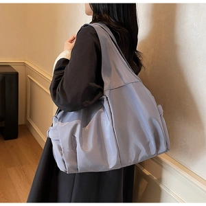 Détail du grand sac cabas gris bleu avec large bandoulière porté par un mannequin