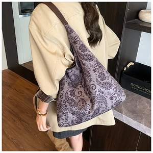 Detail of vintage paisley printed tote bag with broad shoulder strap on shoulder