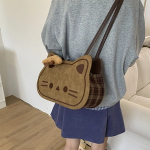 Close-up of cat-shaped brown crossbody bag with plaid side panels and a plush bear charm