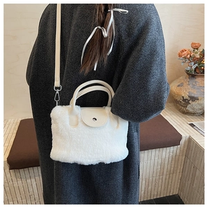 White faux fur bucket bag with leather strap shown on model in cozy home setting