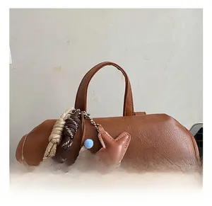 Detail of a brown lychee leather backpack featuring a plush bear and star charm on the handle