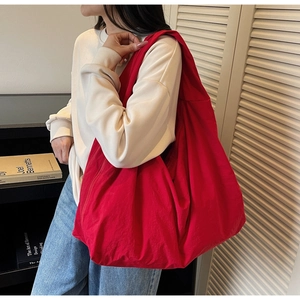 Vue latérale d'un grand sac fourre-tout rouge en nylon porté par un mannequin