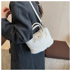 Detail of white plush faux fur crossbody bag with leather strap on a grey coat