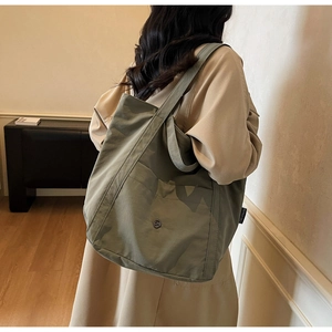 Detail of army green nylon tote bag with magnetic front pocket and soft texture