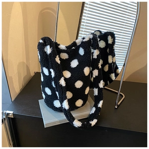 Close-up of black and white polka dot plush tote bag showing soft fleece texture