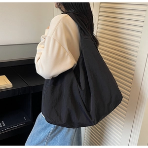Détail d'un grand sac fourre-tout noir mat à texture souple porté à l'épaule