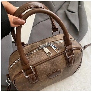 Detailed macro of vintage brown boston bag with dual silver zippers and textured leather