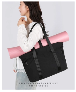 Détail des sangles latérales pour tapis de yoga rose sur le sac cabas noir